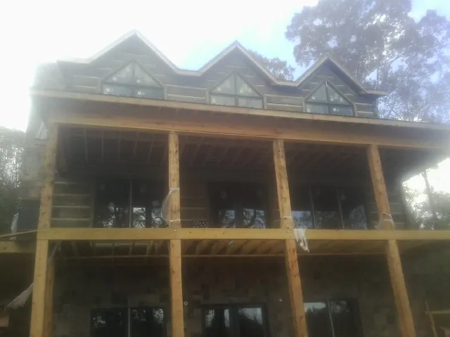 Dormers and porch framing on a large log home under construction — Roof Coating work by our crew in Towson