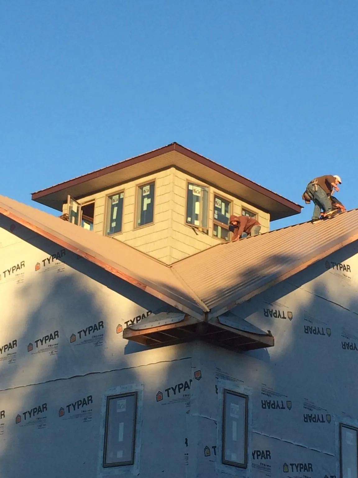 Roofers working around a rooftop cupola on a new metal roof at sunset — Roof Waterproofing in Towson by Roofing Brothers